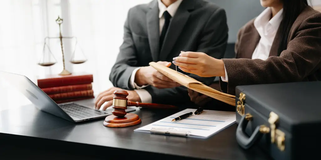 addressing all your servicenow legal service delivery faqs A man and woman in business attire collaborate on a laptop, representing ServiceNow Legal Service solutions.